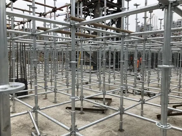 Galvanized ringlock shoring grid on a concrete slab, with base jacks and rosette joints visible
